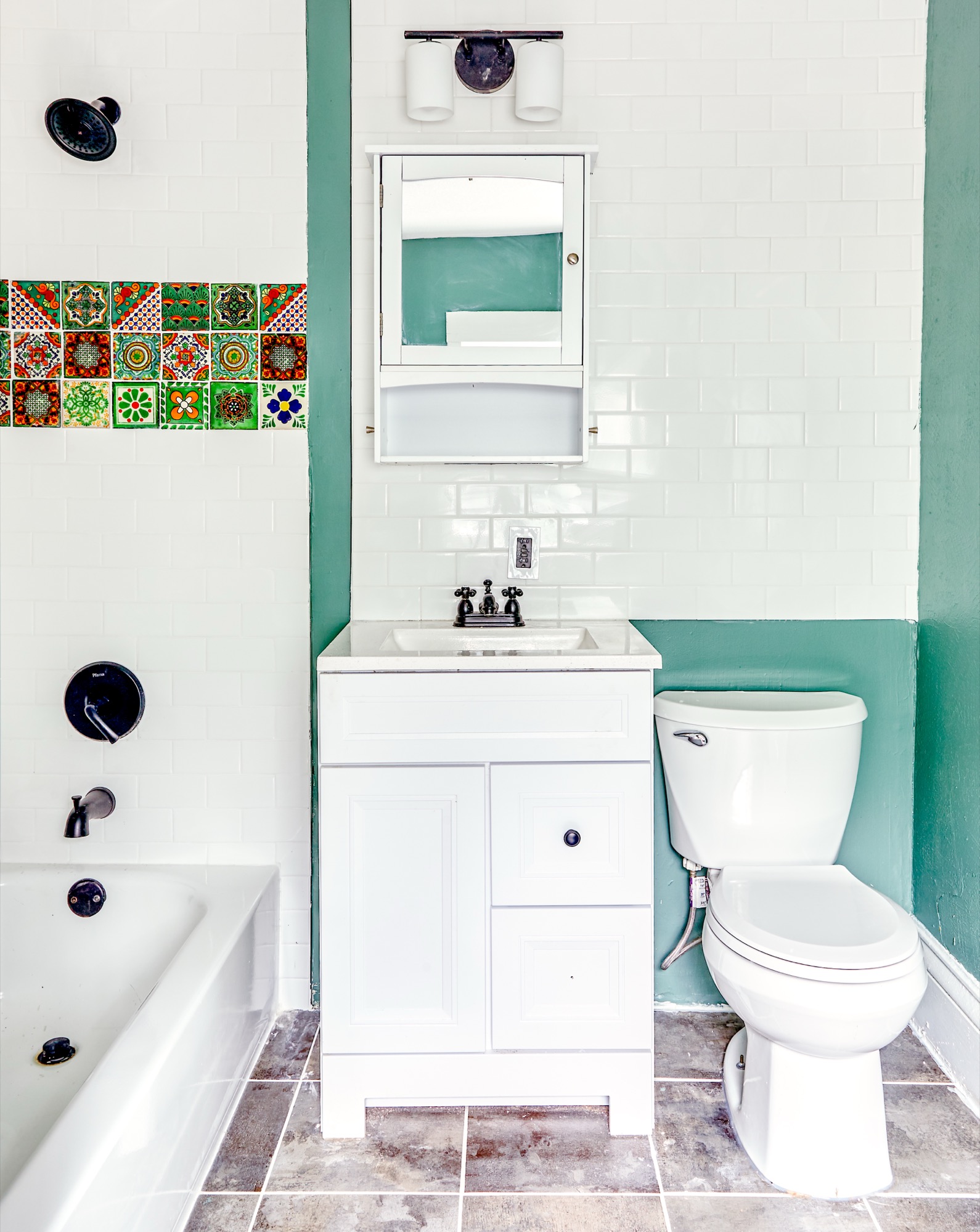 Bathroom with a patterned green-tile accent and a clean white vanity
