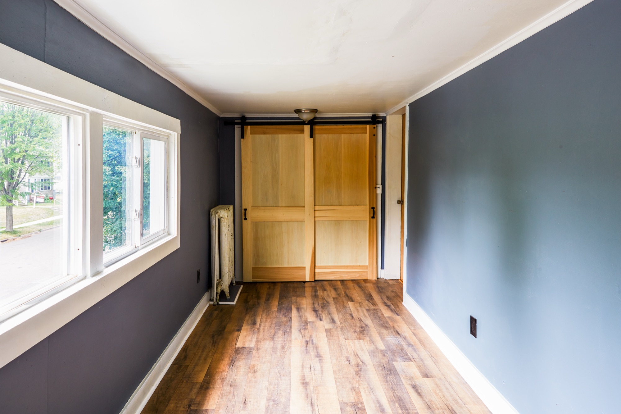 Light-filled bedroom with a sliding barn door and refinished floors
