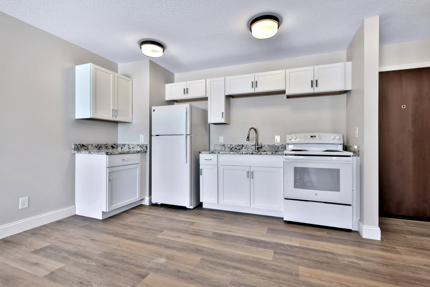 A bright white kitchen with shaker cabinets and warm wood floors