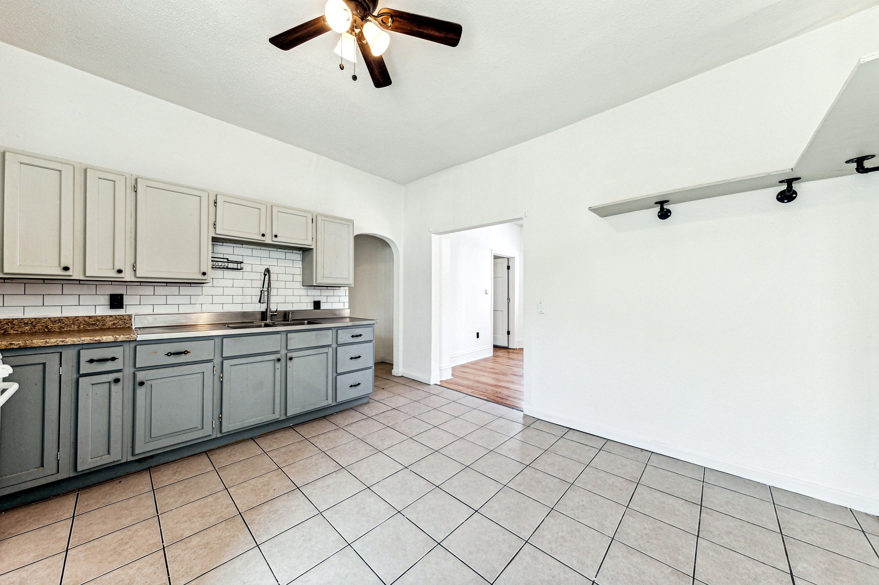 A galley kitchen with sage-grey cabinetry and a tile floor