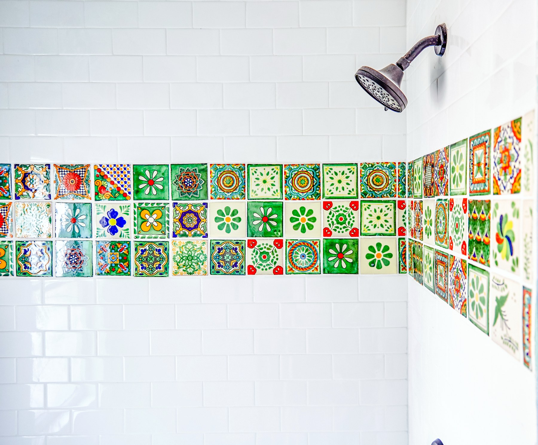 A tiled shower with a hand-set patterned talavera accent band
