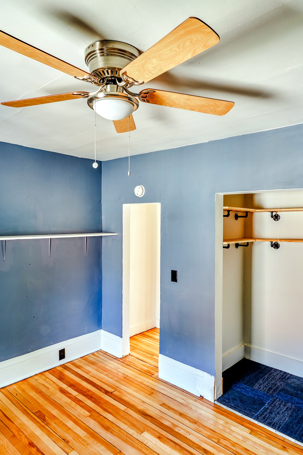 A renovated bedroom with a blue accent wall and warm wood floors