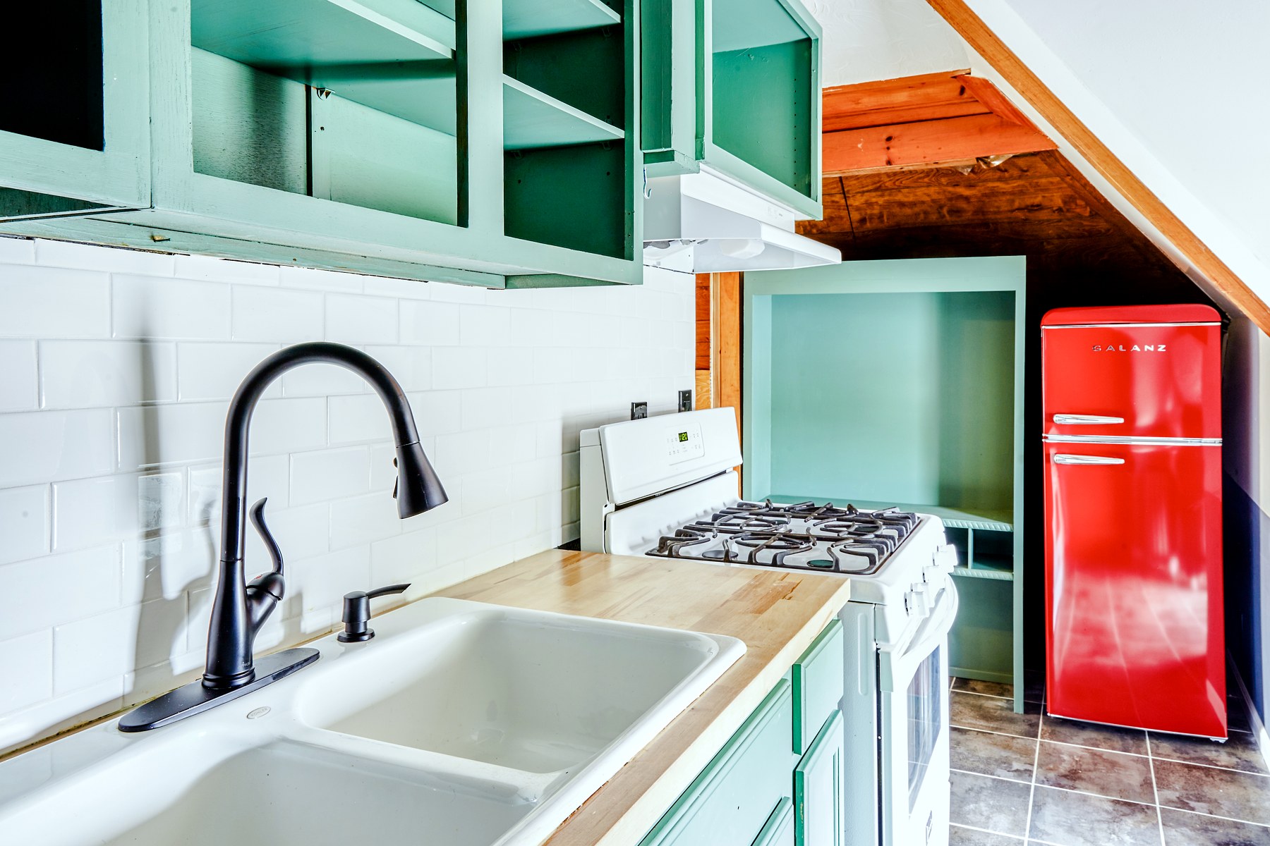 A character kitchen with mint-green cabinets, butcher block, and a red retro refrigerator