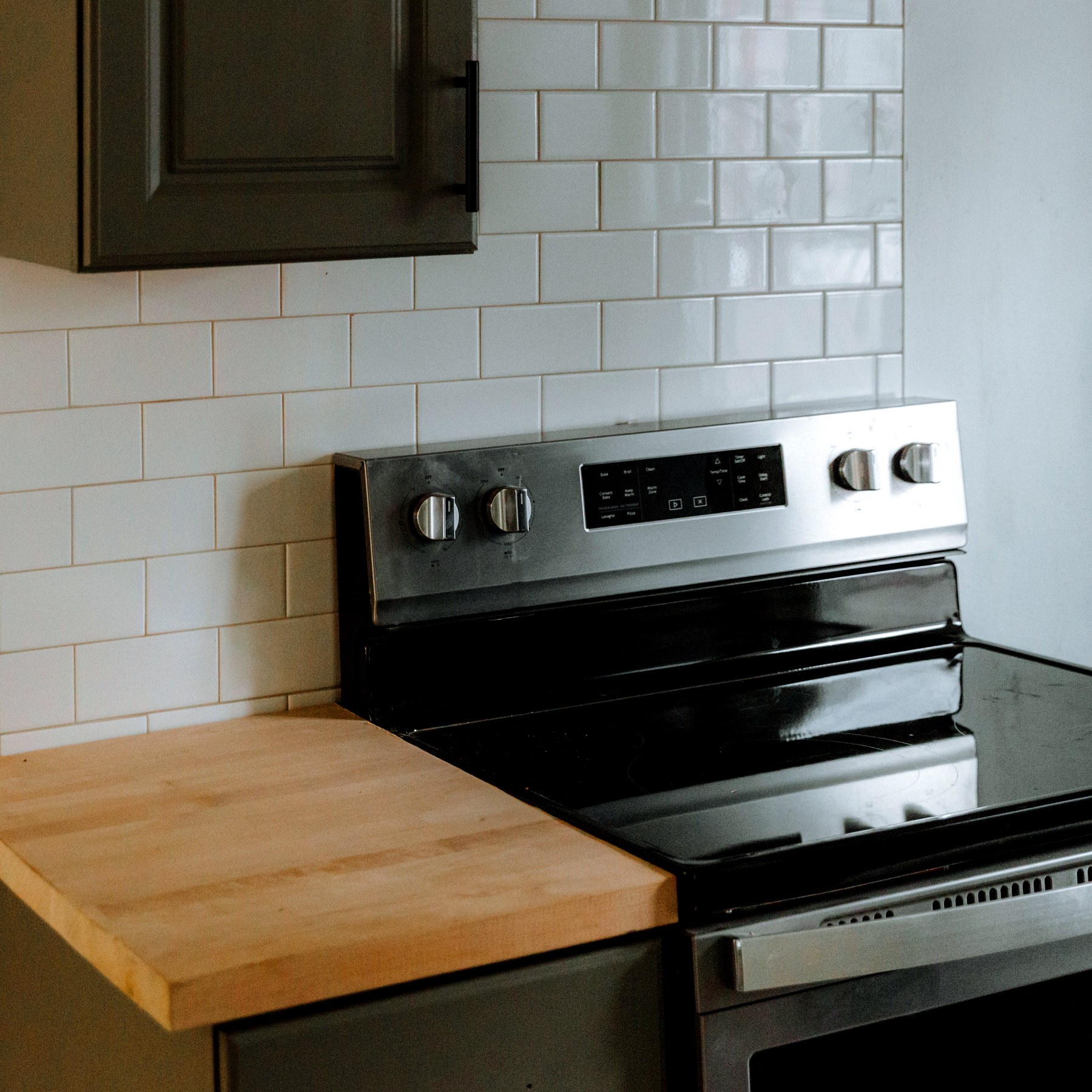 A subway-tile renovation detail with a deep-green cabinet