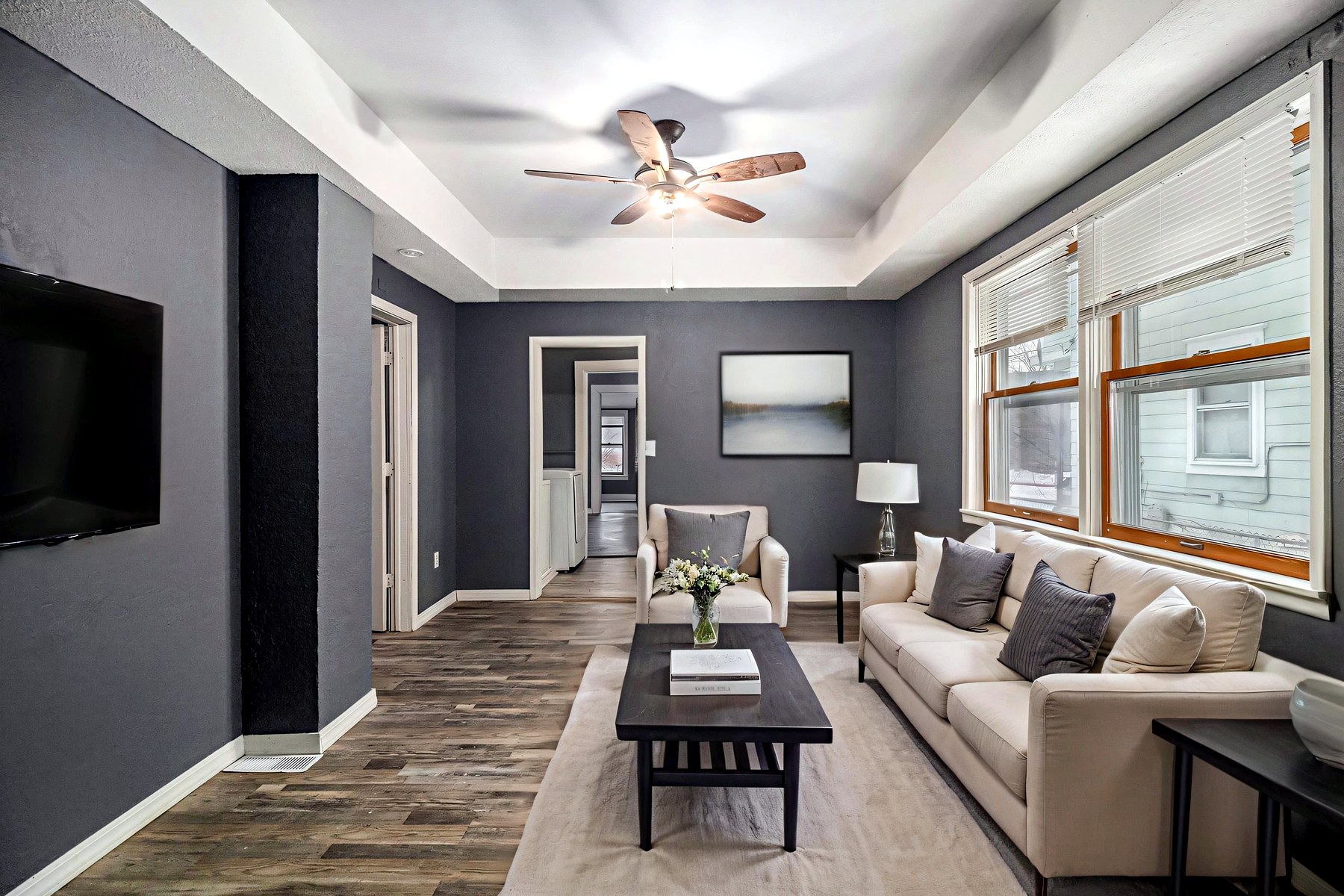 A staged living room opening to the kitchen, with layered furnishings