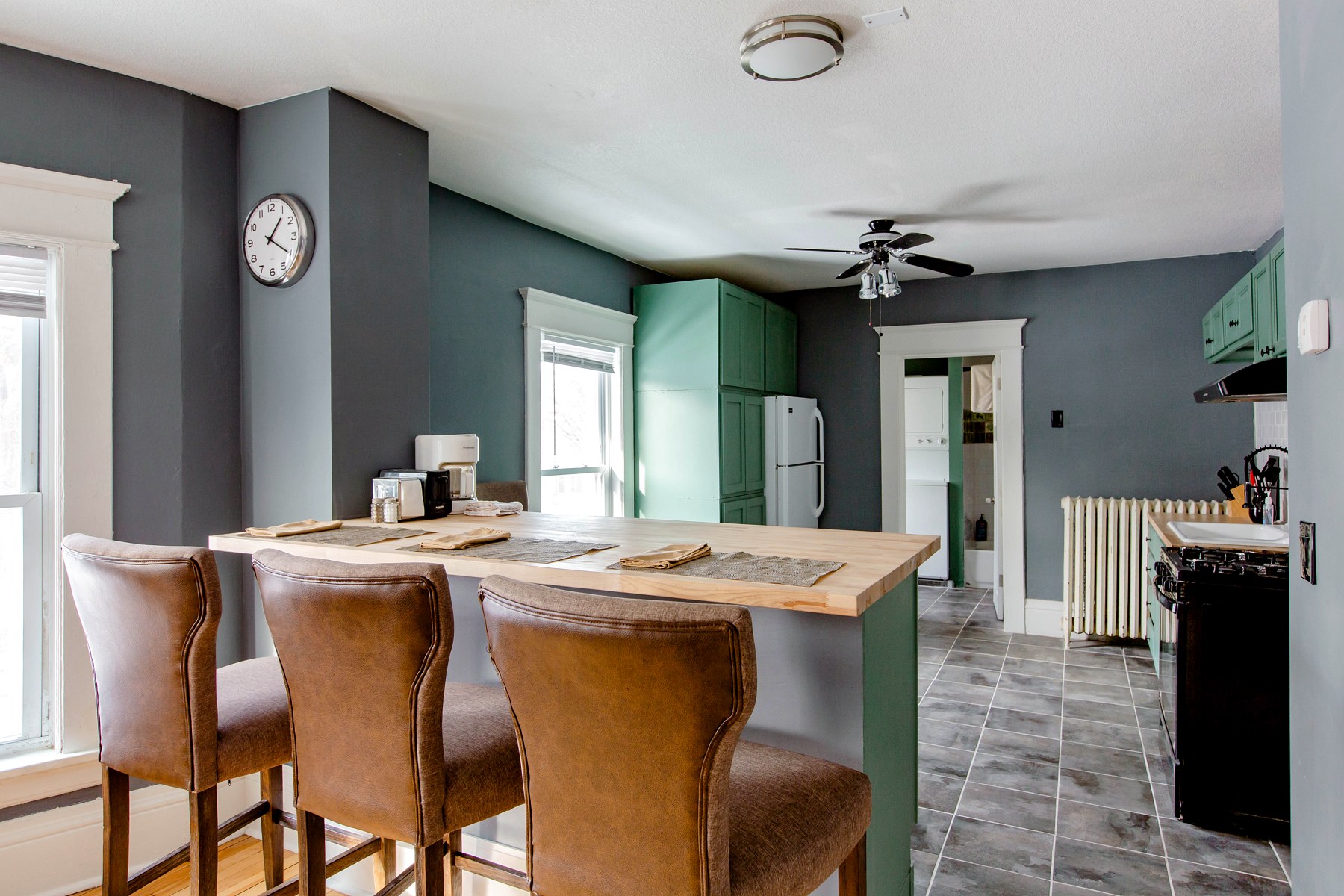 A kitchen breakfast bar with counter seating and a green accent wall
